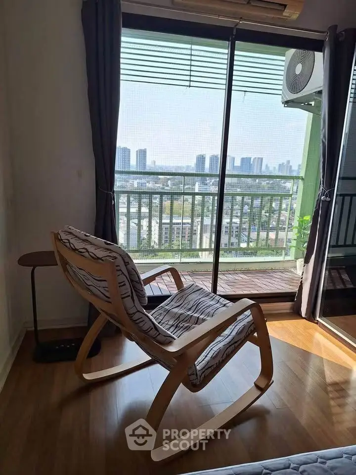 Charming living room with rocking chair and balcony view of city skyline.