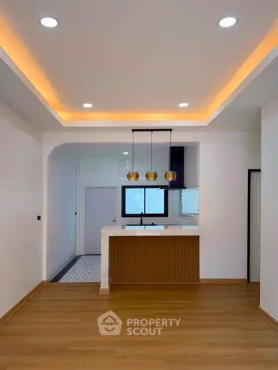 Modern open-layout kitchen with stylish lighting and wooden flooring, perfect for contemporary living.
