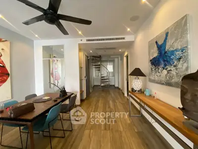 Stylish modern living room with wooden flooring and spiral staircase, featuring elegant decor and contemporary art.