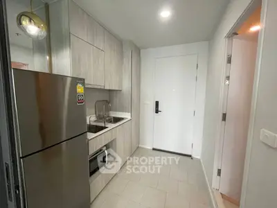 Modern compact kitchen with sleek cabinetry and stainless steel appliances in a stylish apartment.