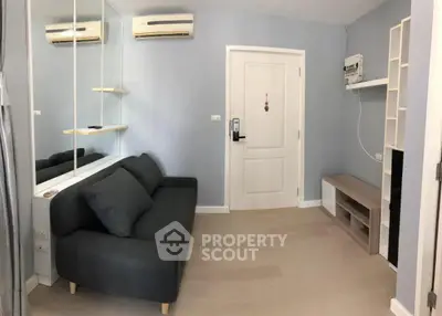 Modern living room with sleek gray sofa and wall-mounted air conditioning unit.