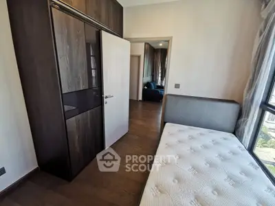 Modern bedroom with wooden flooring and large window offering natural light.