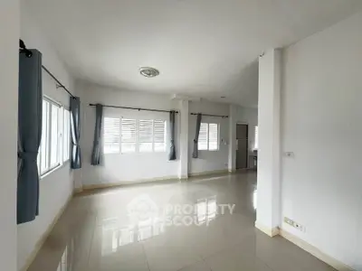 Spacious and bright living room with large windows and tiled flooring