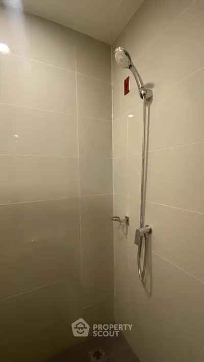 Modern bathroom shower area with sleek tile design and chrome fixtures.