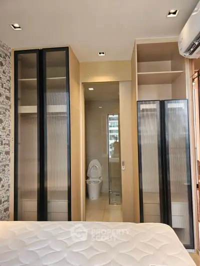 Modern bedroom with built-in wardrobes and ensuite bathroom in a stylish apartment.