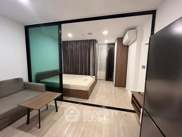 Modern studio apartment with sliding glass partition, cozy living area, and air-conditioned bedroom.