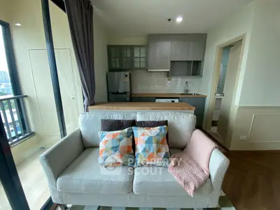 Modern living room with cozy sofa, colorful cushions, and open kitchen layout in a stylish apartment.