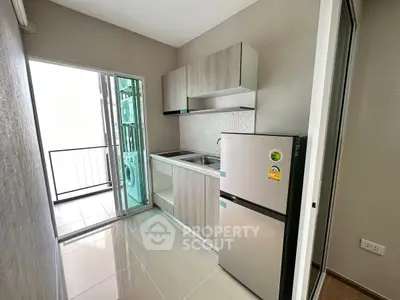 Modern compact kitchen with balcony access and sleek appliances in urban apartment.