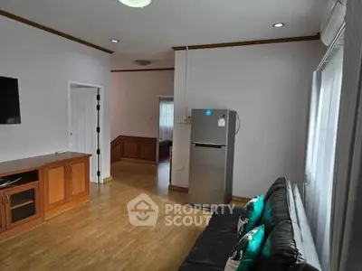 Spacious living room with modern decor and sleek refrigerator, perfect for comfortable living.