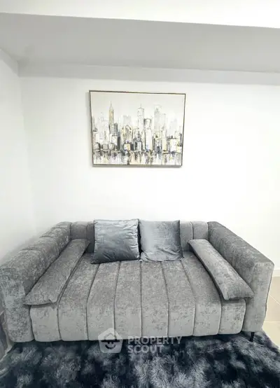Elegant living room with plush gray sofa and modern cityscape artwork.