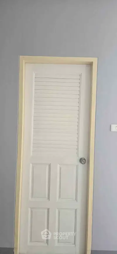 Minimalist white interior door with louvered design in modern home