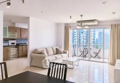 Spacious modern living room with open kitchen and city view balcony in high-rise apartment.