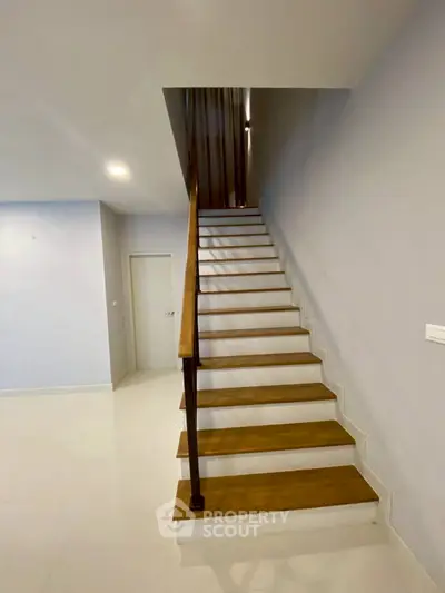 Modern staircase with wooden steps and sleek design in a contemporary home interior.
