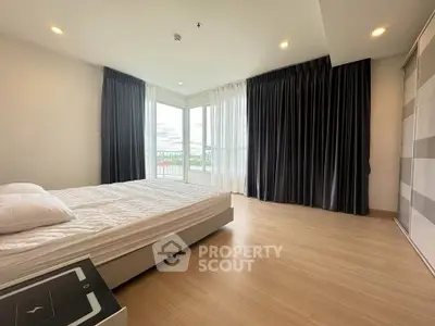 Spacious bedroom with large windows and modern decor, offering a serene view and ample natural light.