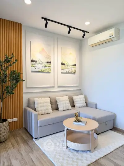 Modern living room with stylish decor, featuring a cozy sofa, elegant wall art, and a sleek air conditioning unit.