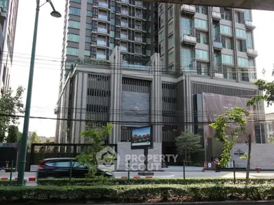 Modern high-rise building exterior with urban street view and lush greenery.