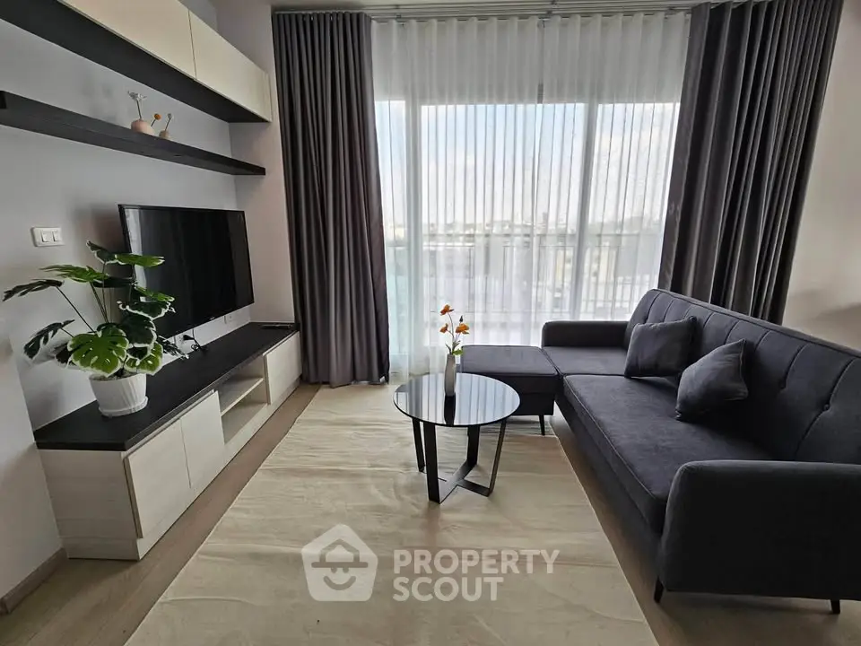 Modern living room with sleek furniture and large window offering natural light.