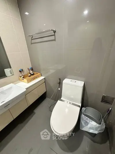 Modern bathroom with sleek fixtures and neutral tones, featuring a stylish vanity and toilet.