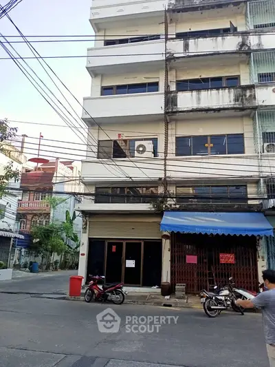 Urban street view of a multi-story residential building with motorbikes parked outside.