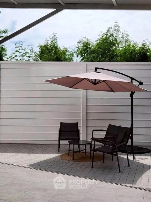 Modern outdoor patio with stylish furniture and umbrella, perfect for relaxation and entertainment.