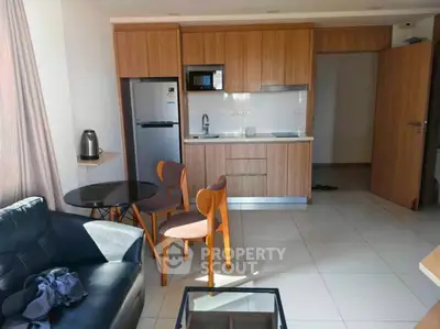 Modern apartment interior with compact kitchen and cozy dining area, featuring sleek wooden cabinetry and natural light.