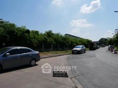 Spacious road view with lush greenery and clear blue sky, ideal for real estate development.