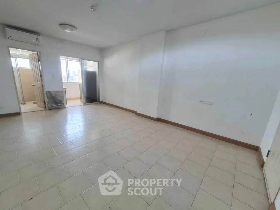 Spacious unfurnished room with tiled flooring and natural light, ideal for customization.