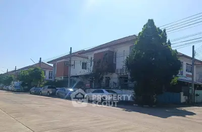 Charming suburban street with modern townhouses and parked cars under a clear blue sky.