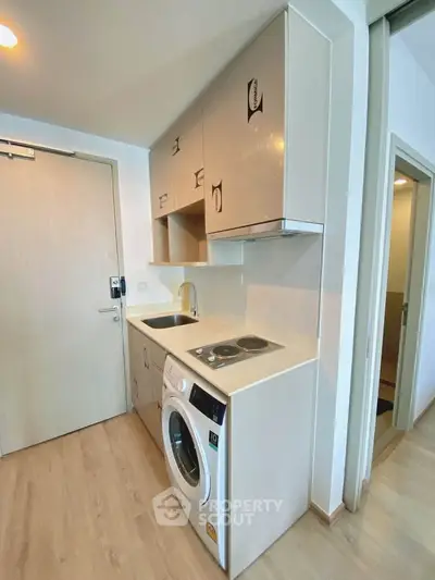 Modern compact kitchen with washing machine and electric stove in a stylish apartment.