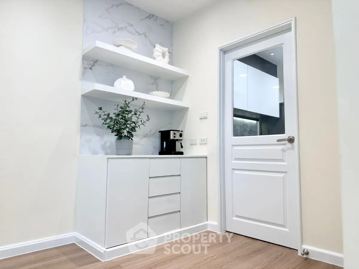 Modern kitchen corner with sleek white cabinetry and built-in coffee machine