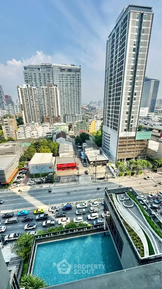 Stunning cityscape view from high-rise building with pool and bustling street below.