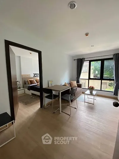 Modern living room with dining area and large window offering natural light.