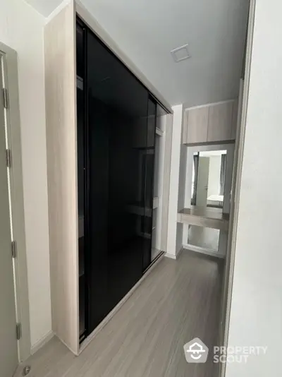 Modern hallway with sleek black sliding wardrobe and minimalist vanity mirror