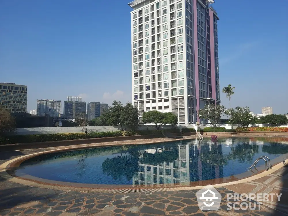 Luxurious high-rise condominium with a stunning reflective pool set amidst a lush garden, offering a tranquil urban oasis with a modern architectural backdrop.