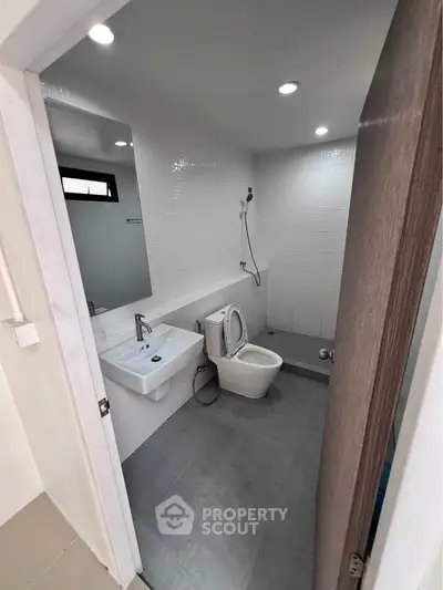Modern bathroom with sleek fixtures and minimalist design, featuring a wall-mounted sink and shower area.