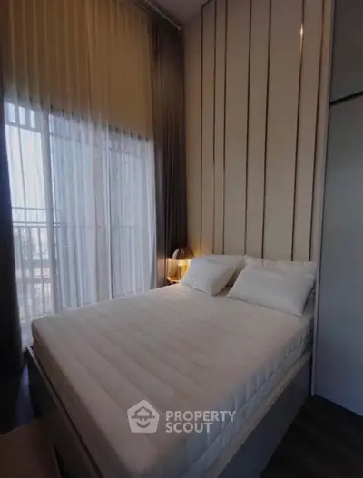 Cozy bedroom with large window and modern decor in a stylish apartment.