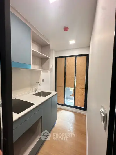 Modern compact kitchen with sleek cabinetry and large window for natural light.