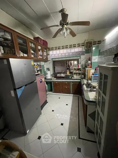 Charming kitchen with ample storage and modern appliances, featuring a ceiling fan and tiled flooring.
