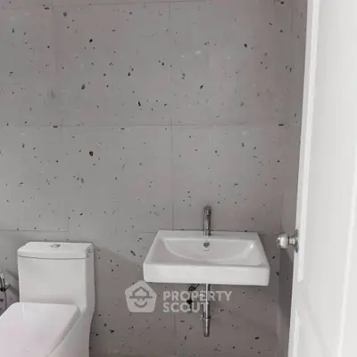 Modern minimalist bathroom with sleek fixtures and terrazzo wall tiles.