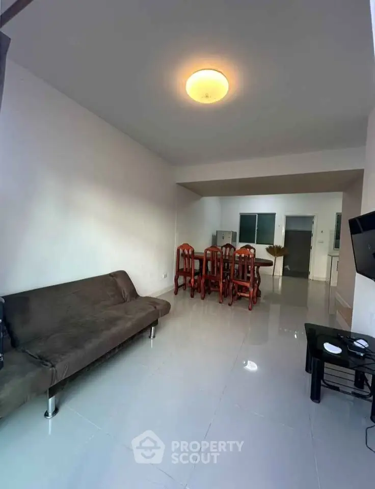 Spacious living room with modern furniture and dining area in open layout apartment.