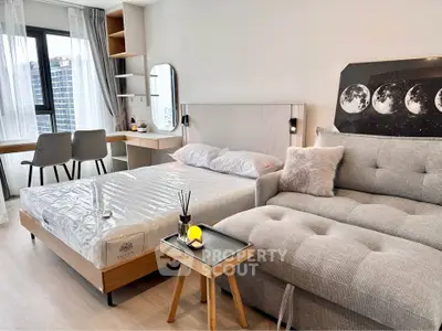 Modern studio apartment with stylish decor, featuring a cozy bed, chic sofa, and functional workspace.