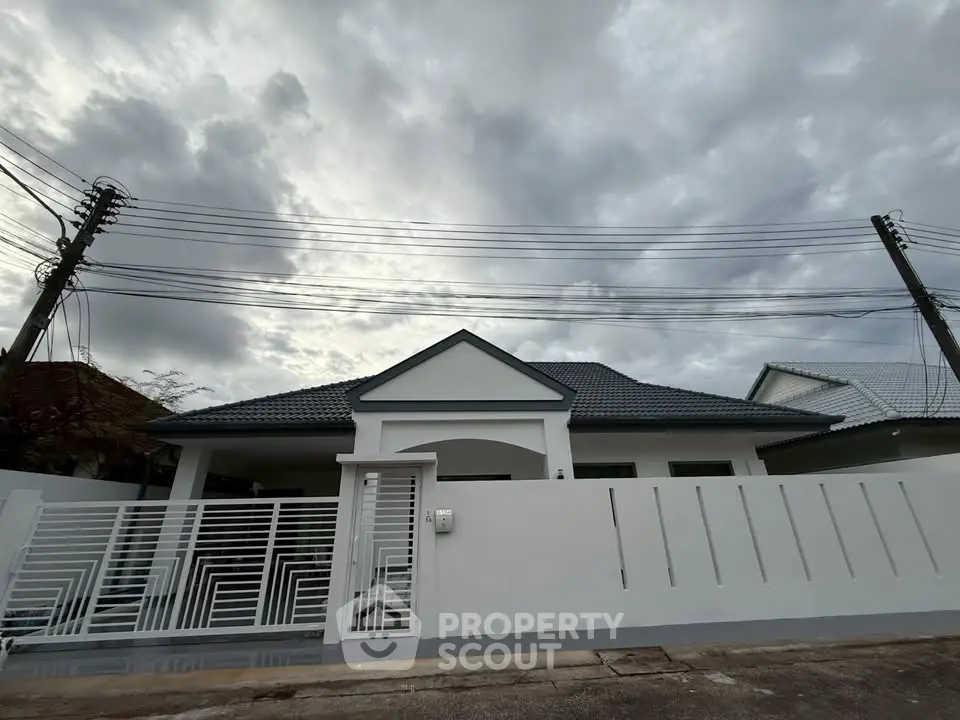 Charming single-story home with modern white facade and secure gated entrance.