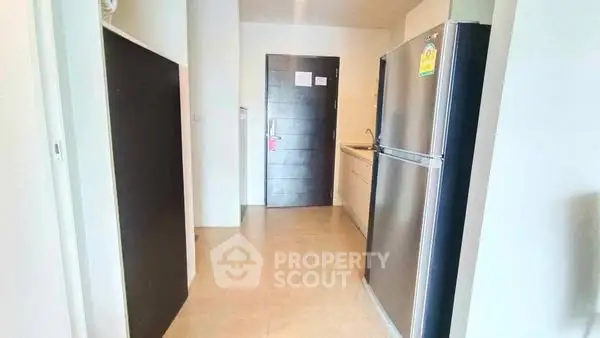 Modern apartment entrance with sleek kitchen and stainless steel fridge