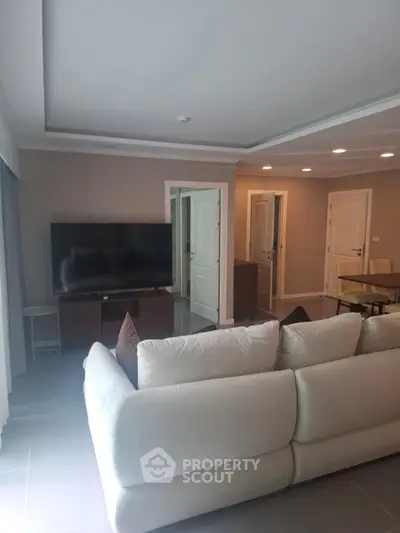 Spacious living room with modern decor and large TV, perfect for relaxation and entertainment.