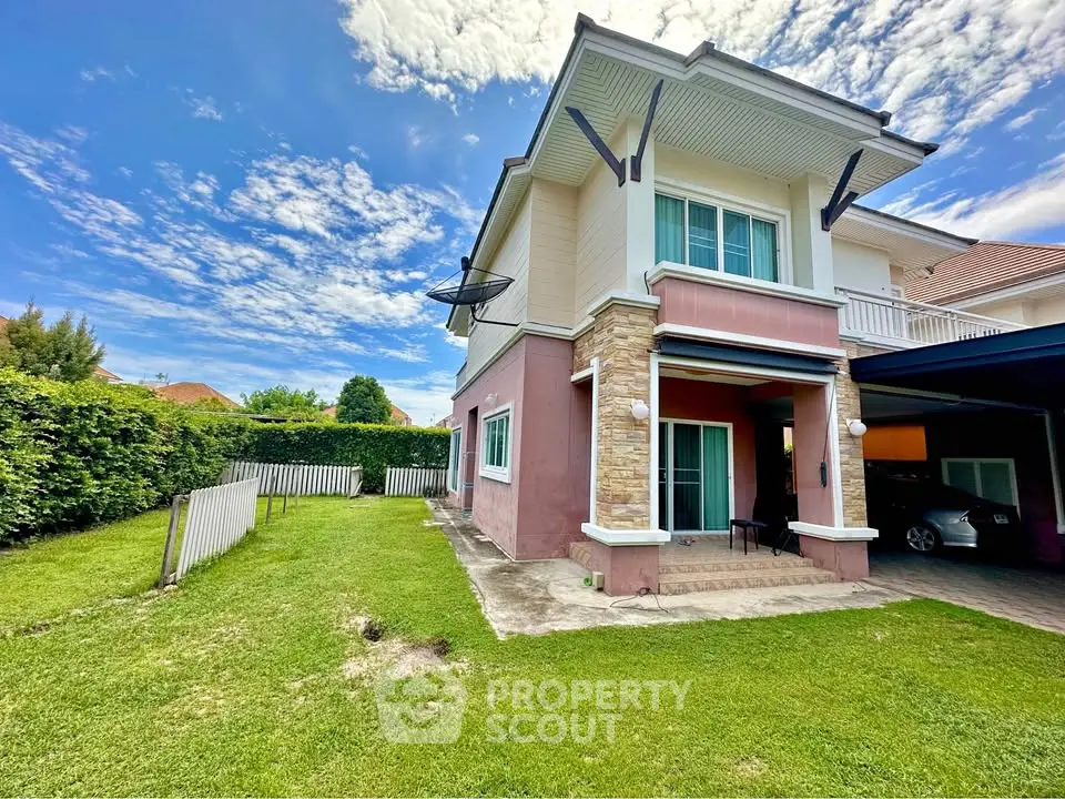 Charming two-story house with lush green lawn and carport, perfect for family living.
