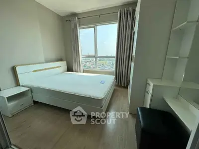 Bright and airy bedroom with large window and modern furnishings in a high-rise apartment.