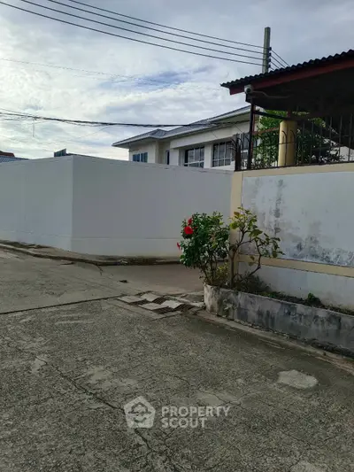 Charming residential property with a white exterior wall and lush greenery in a serene neighborhood.