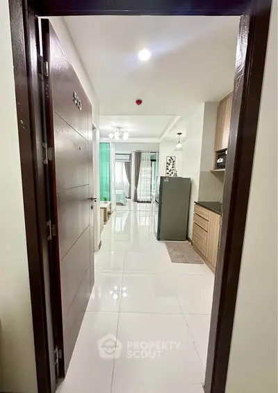 Modern apartment entrance with sleek kitchen and bright living area, perfect for urban living.