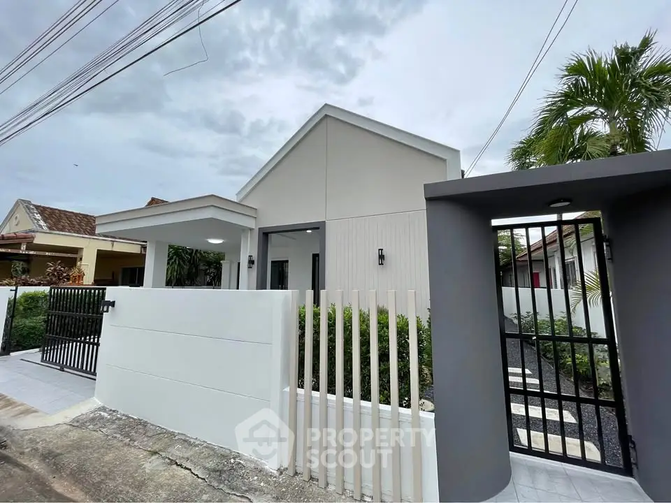 Modern minimalist house exterior with sleek design and gated entrance, showcasing contemporary architecture.