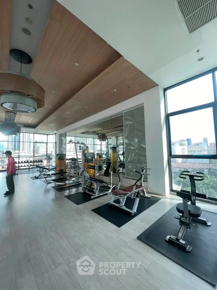 Spacious modern gym with large windows and fitness equipment in a luxury residential building.